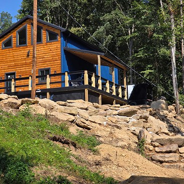 Log cabin on a stone hillside surrounded by trees